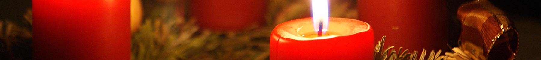 four red candles on a wreath of green pine branches