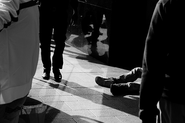 a business man hurriedly walking past a homeless man on a sidewalk