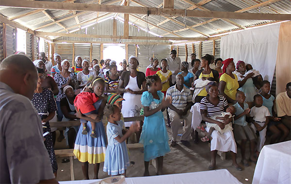 people singing and praying in a small rough church in Haiti