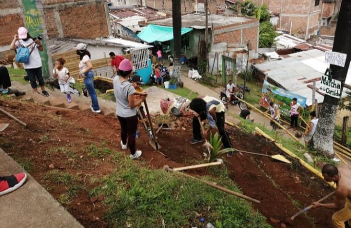 Gente trabajando en una huerta comunitaria con canteras.