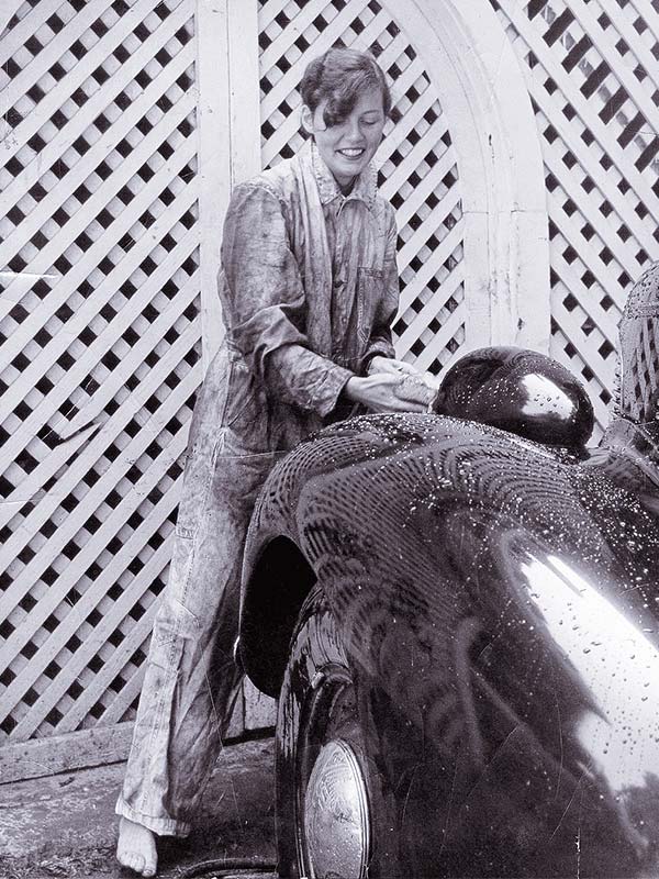 photo of a young woman fixing a car