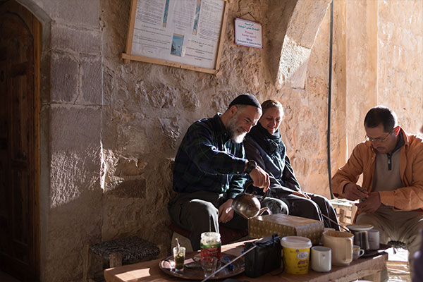 people enjoying mate in the sunlight by a wall