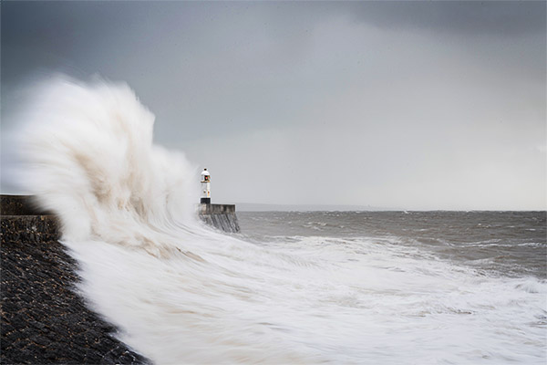 huge wave washing over a lighthouse