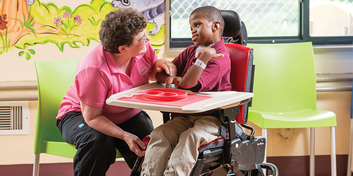 A therapist talking to a child in a Rifton Activity Chair