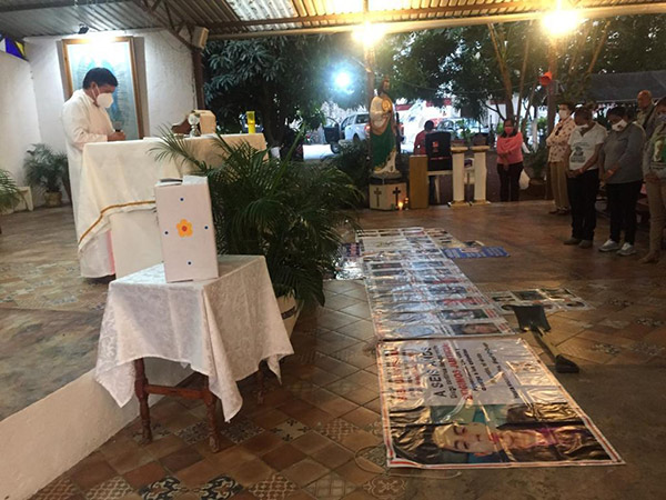 Priest saying Mass with a peace mailbox on table near altar.