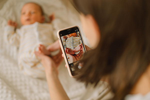 Mother taking photo of baby boy on mobile phone