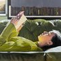 a woman reading a book on a green sofa