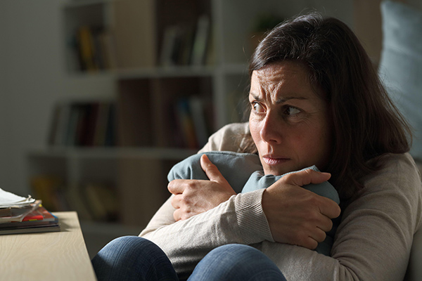 a frightened woman clutching a pillow