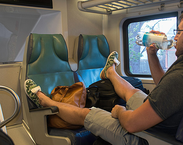 A rude man taking up too many seats on a train.