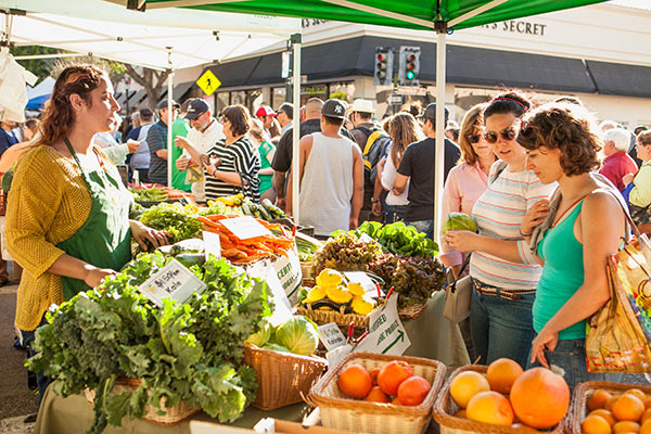 people shopping at an open air farmers market