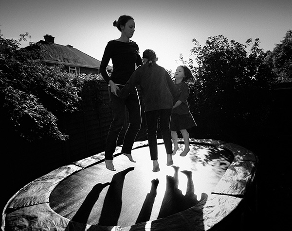 a mother and kids jumping on a trampoline