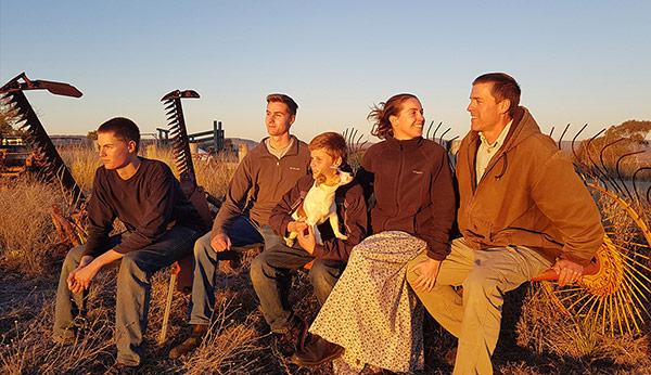 Picture of parents and three sons sitting in brown landscape