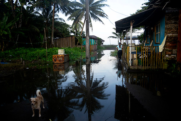 a woman walks to reach the beach covered with water due to the high tide