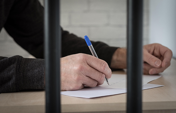 a man writing a letter behind bars
