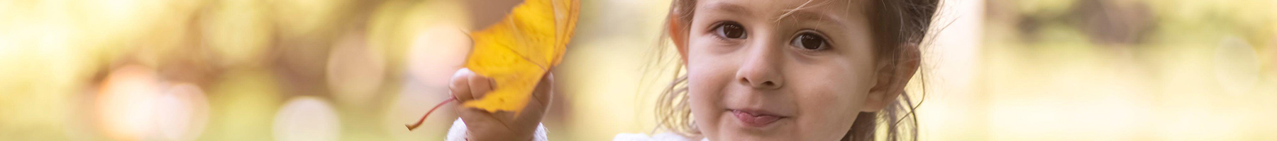 a child holding a yellow leaf