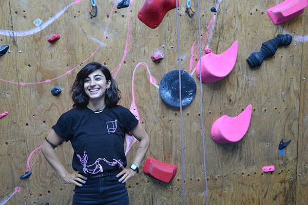 a woman standing next to a climbing wall