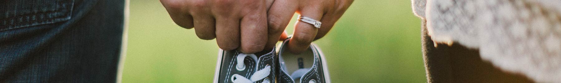 A married couple holding baby shoes in their clasped hands.