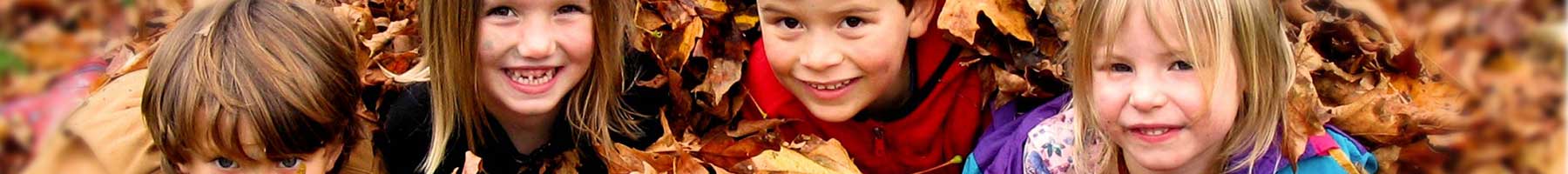 four happy children in a pile of brown leaves