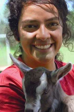 A young woman holding a goat.