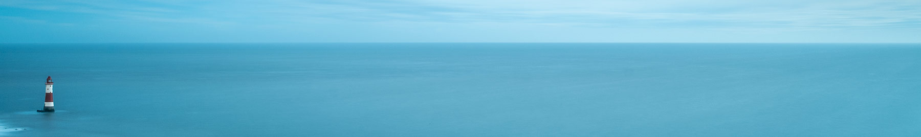 tiny lighthouse by huge sea and sky