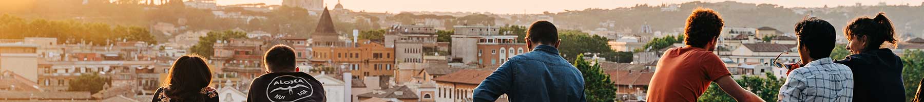 friends sitting and leaning on a wall looking at the view of an Italian city