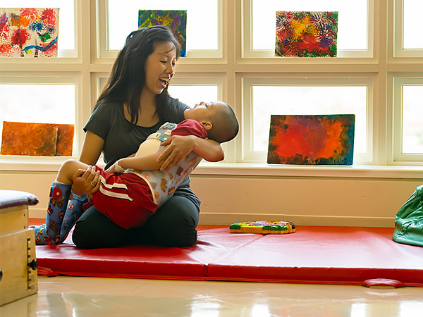 physical therapist holding a child wearing braces in a sunny room