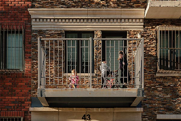 children on the balcony of a brick house