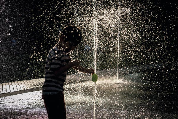 a boy playing in a fountain of water