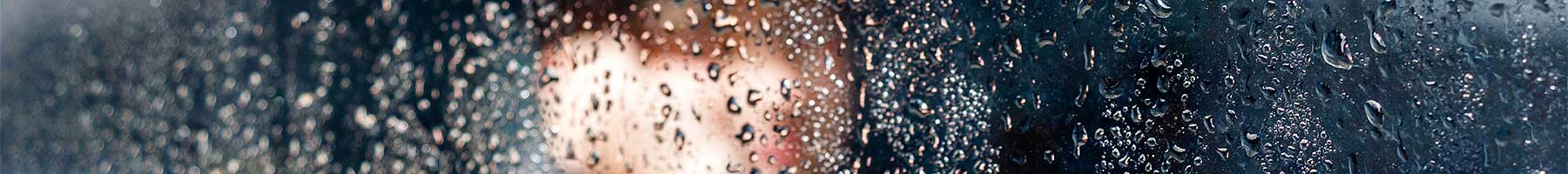 photo of a child looking through a rain covered window