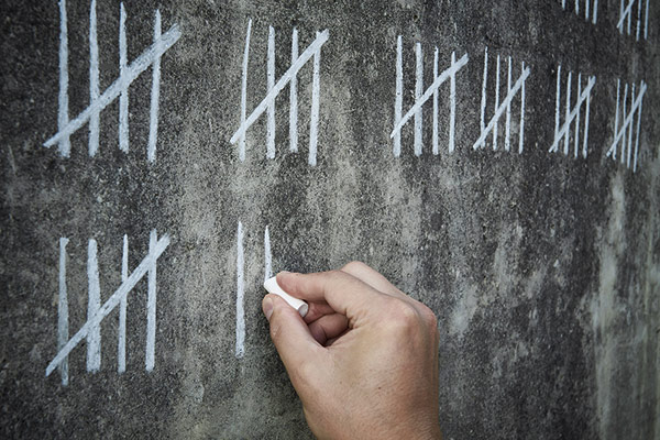 chalk tally marks being drawn on a blackboard