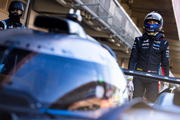 a driver standing behind a racing car