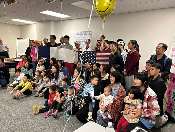 large group of people posing for a photo with balloons and flags