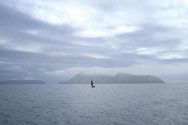 small boat on the ocean with islands in the background