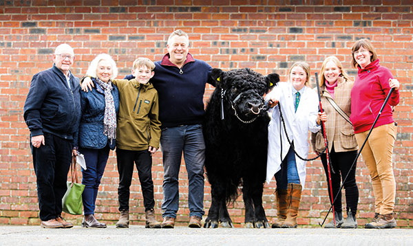 a few people posing for a photo with a cow